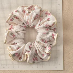 Detail of cream floral knit scrunchie showing 12cm size on scale measurement board