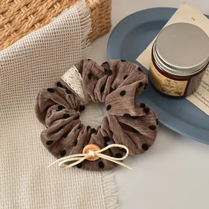 Detail of vintage velvet polka dot scrunchie with lace edge and wooden button decoration