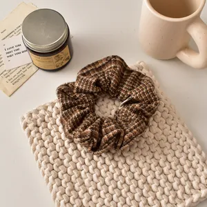 Gros plan d'un chouchou en tweed à carreaux marron sur un tissu en maille douce