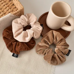 Three premium corduroy scrunchies in earth tones displayed in a cozy home setting