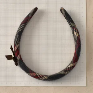Close-up of vintage red plaid headband with dark brown bow and scale measurement details