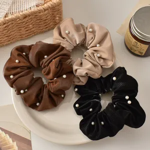 Detail of plaid scrunchies with white pearls in dark brown, beige, and black colors