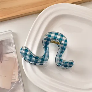 Detail der blau-weißen gewellten Haarklammer mit Karomuster auf einem Porzellanteller