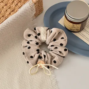 Detail of velvet polka dot scrunchie with lace edge and handmade wood button decoration