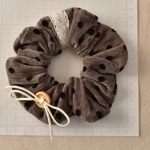 Detail of velvet polka dot scrunchie with lace trim and engraved wooden button decoration