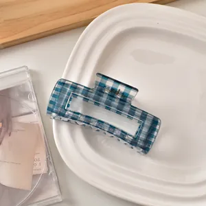 Detail der blau-weiß karierten Haarklammer auf einem minimalistischen Keramiktablett