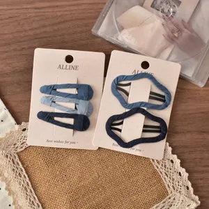 Detailset blauer Stoff-Haarclips auf einer eleganten beige-farbenen Displaykarte