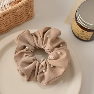 Plaid faux leather scrunchie with pearls in a cozy beige setting with candles