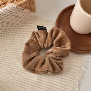 Macro detail of brown velvet scrunchie with white ORIGINAL woven label on fabric