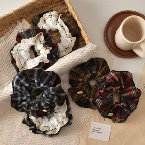 Close-up of retro plaid hair scrunchies with white lace edges in a rustic setting