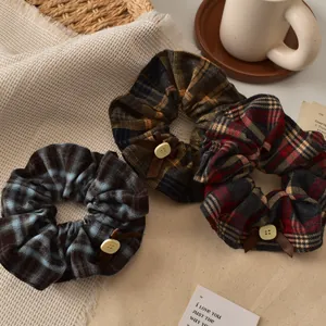 Detailed set of three plaid scrunchies with decorative buttons and ribbon bows