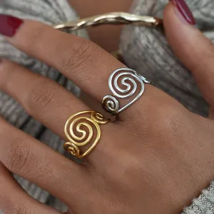 Detail shot of a person wearing gold and silver spiral rings over grey knitwear