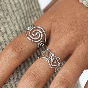 Close-up of silver hollow spiral and rose flower ring designs on model's finger