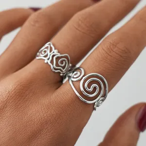 Detail of silver rose and spiral hollow rings with adjustable band on model finger