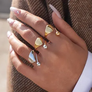 Anillo abierto triangular irregular en oro y plata en una modelo con chaqueta elegante