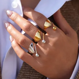 Detalle de anillos abiertos triangulares irregulares en oro y plata en los dedos