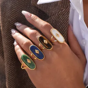Detailed view of gold oval rings with turquoise, lapis, tiger eye and white stone inlays