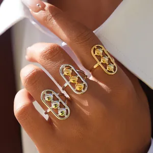 Tres anillos geométricos con cuentas móviles en oro y plata en la mano de modelo