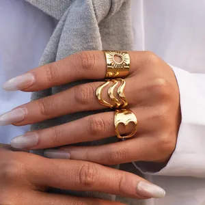 Primer plano de anillos dorados con diseños de sol, líneas onduladas y corazón