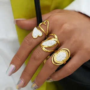 Three gold-plated stainless steel rings with white crystals worn by a female model