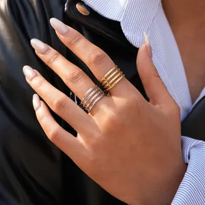 Detailed view of layered 18K gold and silver minimalist multi-strand rings on a model