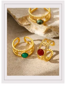 Detail of gold braided open rings with colorful natural stones on stone background