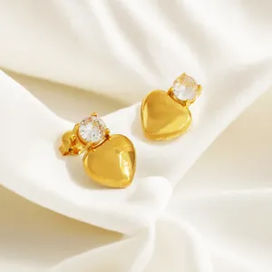 Detail of gold heart earrings with round cubic zirconia on white silk background