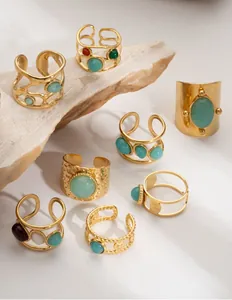 Macro view of eight vintage 18K gold rings with natural stones on a textured rock