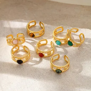 Adjustable gold-plated braided rings set with colorful natural stones on stone texture