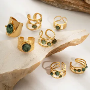 Nahaufnahme von 7-teiligem goldenem Ring-Set mit grünen Natursteinen auf Rohstein