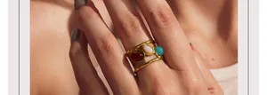 Detail van goudkleurige roestvrijstalen ring met rode witte en groene edelstenen