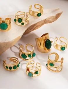 Detailed macro of gold vintage rings with green natural stone inlays on textured stone