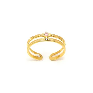 Dettaglio anello dorato a doppio strato con motivo a corona e zircone rosa