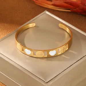 Dettaglio di bracciale rigido dorato con medaglia di San Benedetto e cuore di diamanti