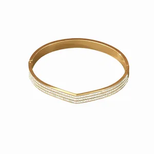 Gold V-shaped geometric bangle with triple-row micro-pave crystals on white background