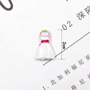 Detailed view of a 2cm white mini tassel charm with gold ring for DIY jewelry making