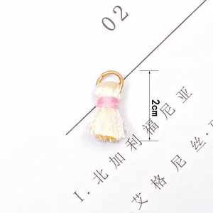 Macro shot of 2cm cream tassel pendant with pink thread and gold ring for DIY jewelry