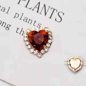 Dettaglio macro di strass in cristallo rosso a cuore con base da cucire dorata