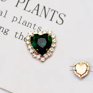 Dettaglio macro del cristallo smeraldo a forma di cuore da cucire con base dorata e strass
