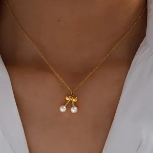 Nahaufnahme der 18K vergoldeten Kirsch-Perlenkette mit Schleifenanhänger am Hals