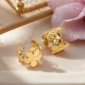 Elegant gold flower hoop earrings with intricate floral design on a soft fabric background