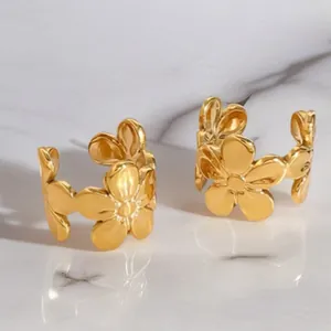 Elegant gold flower hoop earrings with polished floral design on marble surface
