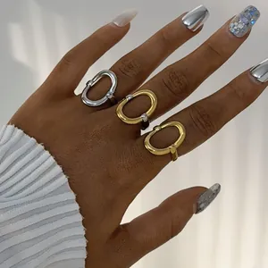 Close-up van een set minimalistische gouden en zilveren ovale ringen om een modelhand