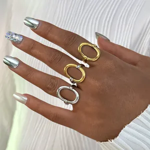 Detail van drie geometrische roestvrijstalen ringen in goud en zilver aan hand
