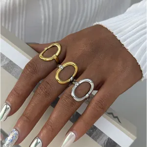 Gepolijste geometrische holle open ringen in goud en zilver getoond op een model