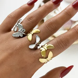 Detail of minimalist stainless steel butterfly rings in gold and silver on hand