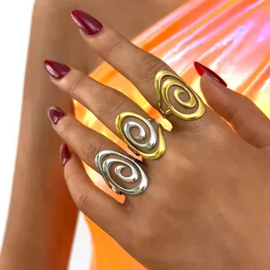 Tres anillos de espiral minimalistas en oro y plata en la mano de una modelo