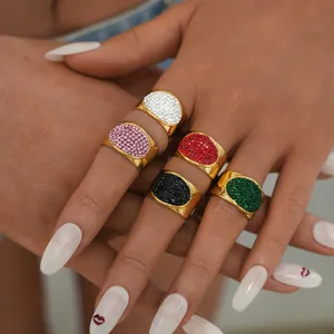 Close-up of five chunky gold oval rings with colorful micro-inlaid rhinestones on hand