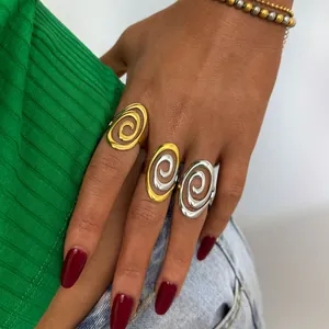 Tres anillos en espiral de colores oro y plata usados juntos en una mano femenina