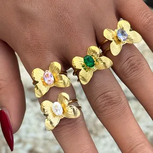 Eleganti anelli a farfalla dorati con pietre di zircone colorate sulla mano di donna